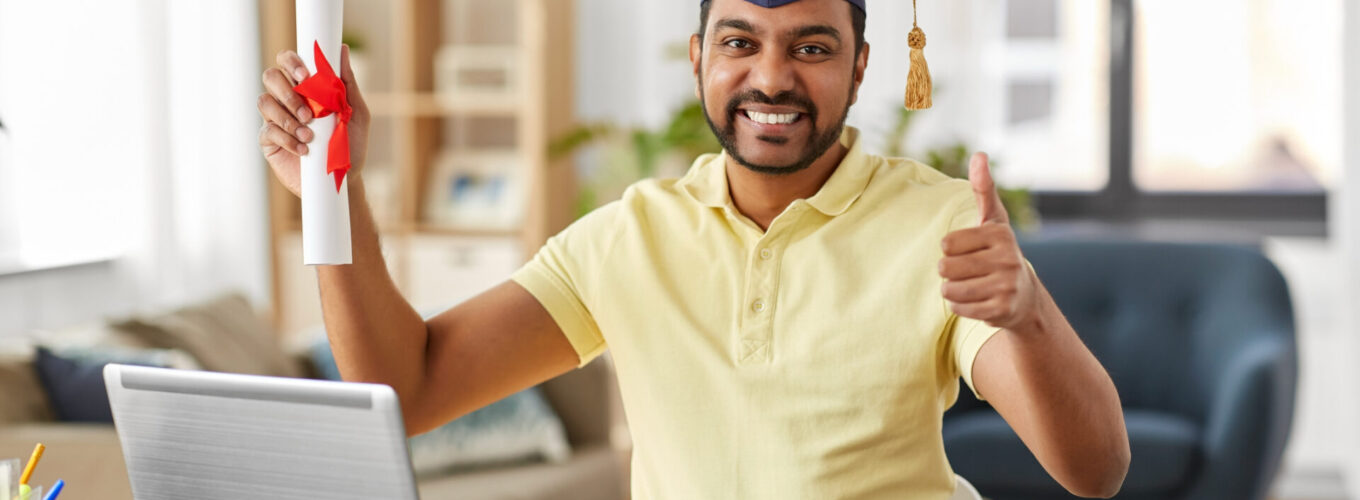 e-learning, education and people concept - happy smiling indian male student with laptop computer and diploma showing thumbs up at home