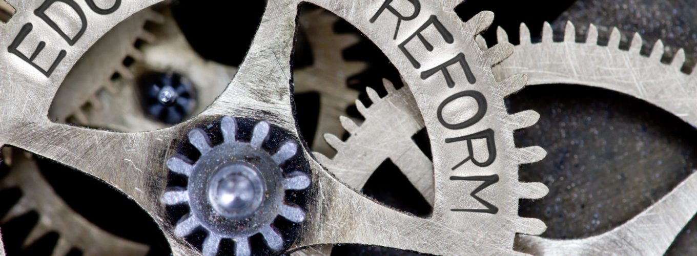 Macro photo of tooth wheel mechanism with EDUCATION REFORM letters imprinted on metal surface