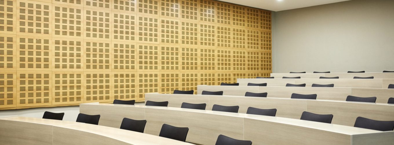 Interior of illuminated lecture hall. Empty chairs are arranged in classroom. Auditorium is in university.